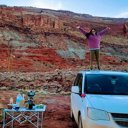 girl standing on van with arms out embracing nature
