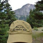 Green cap with 'Sol Terra Shop' logo in a forest setting with mountains in the background