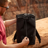 Man holding a black recycled backpack , pulling drawstring