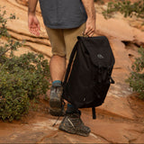 Person hiking on a rocky trail with a black recycled backpack 